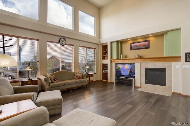 12754 Angelina Dr, Peyton, CO 80831 - living room with healthy amount of natural light, wood finished floors, a tile fireplace, a high ceiling, and built in features