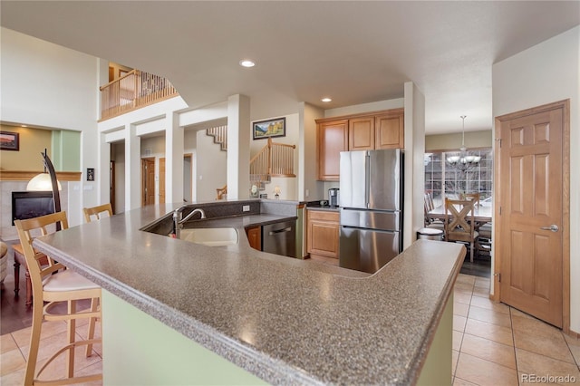 12754 Angelina Dr, Peyton, CO 80831 - kitchen featuring stainless steel appliances, light tile patterned floors, a breakfast bar, recessed lighting, and a tiled fireplace