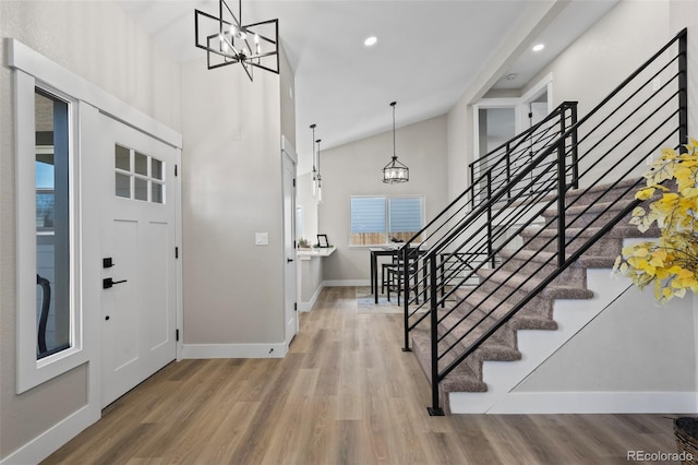 foyer featuring a chandelier, high vaulted ceiling, wood finished floors, and baseboards