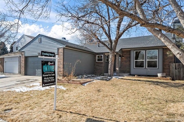 ranch-style home featuring an attached garage, brick siding, concrete driveway, roof with shingles, and a front lawn