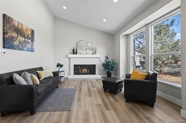 living area featuring a fireplace, recessed lighting, vaulted ceiling, wood finished floors, and baseboards