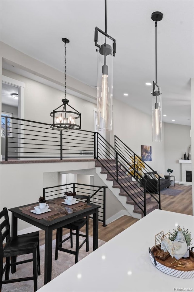 dining space featuring a fireplace, stairway, baseboards, and wood finished floors