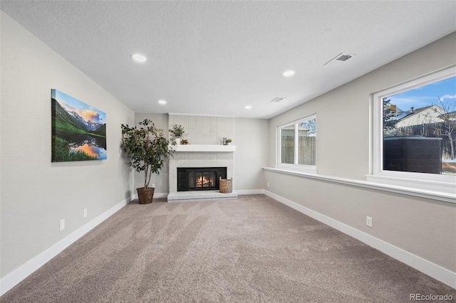 unfurnished living room featuring visible vents, a brick fireplace, carpet flooring, a textured ceiling, and baseboards