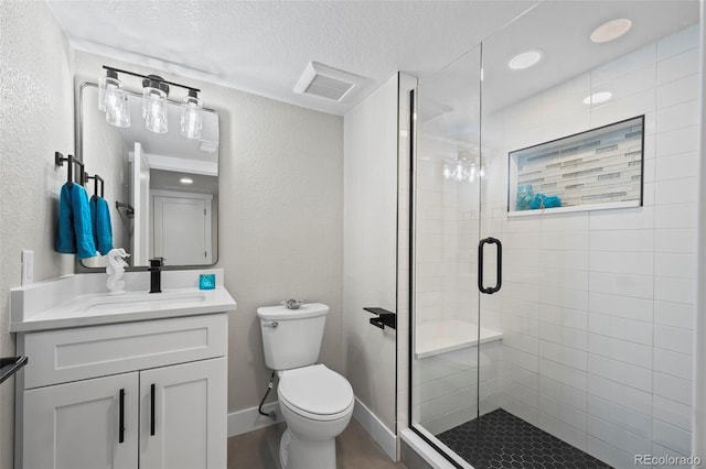 bathroom with a textured wall, toilet, vanity, visible vents, and a stall shower