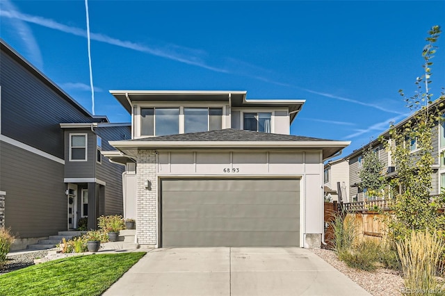 prairie-style house featuring concrete driveway, a garage, fence, and brick siding