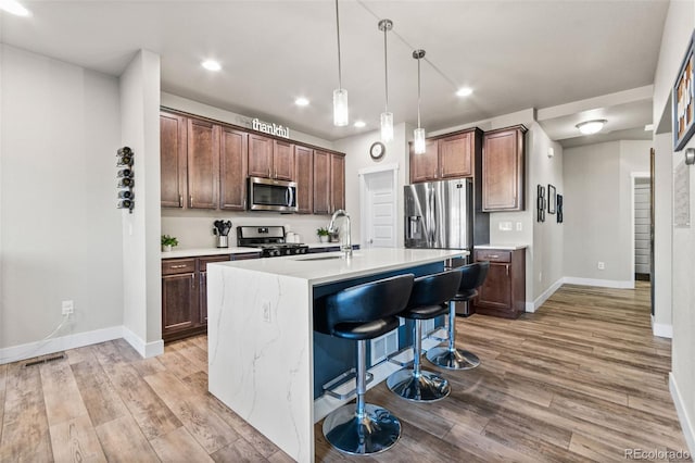 kitchen featuring a sink, stainless steel appliances, light wood-style floors, and light countertops