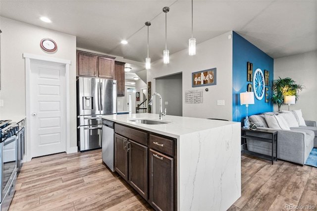 kitchen featuring light wood finished floors, dark brown cabinetry, appliances with stainless steel finishes, and a sink