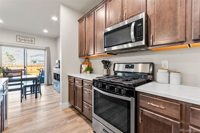 kitchen with baseboards, light wood-type flooring, light countertops, recessed lighting, and stainless steel appliances