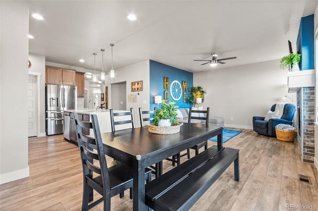 dining room featuring light wood-type flooring, baseboards, visible vents, and a ceiling fan