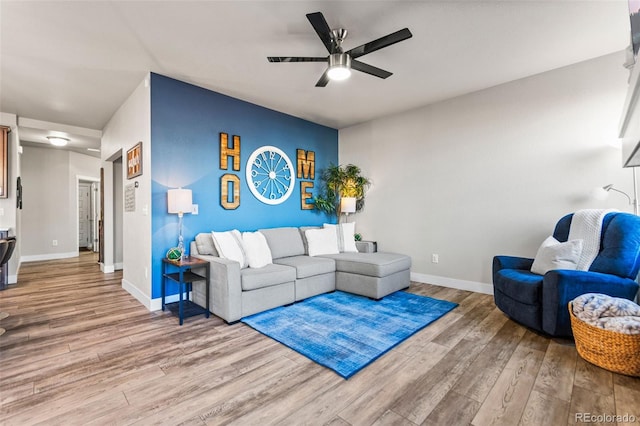 living room featuring light wood finished floors, baseboards, and a ceiling fan