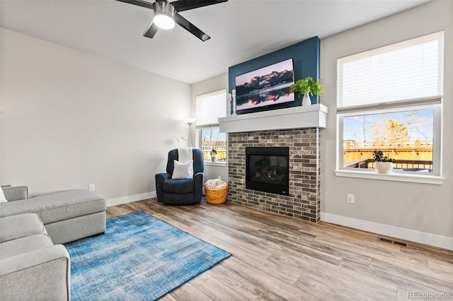 living room featuring visible vents, baseboards, wood finished floors, and a fireplace