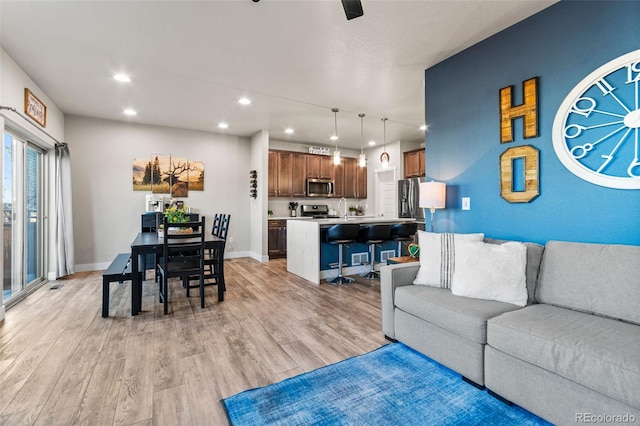 living room featuring recessed lighting, light wood-style floors, and baseboards