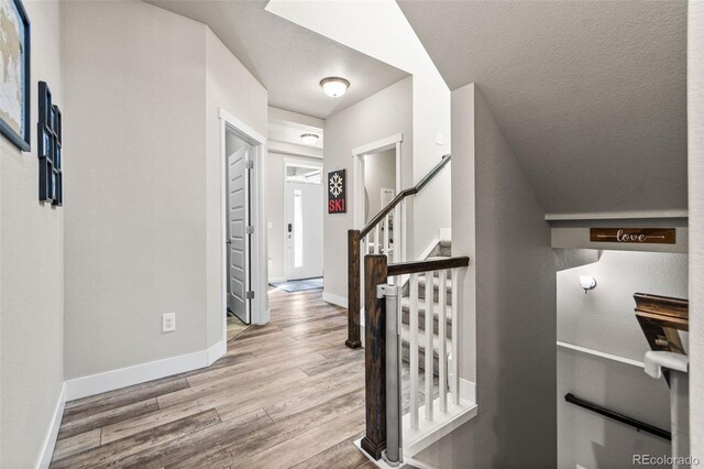 entrance foyer with stairs, wood finished floors, baseboards, and a textured ceiling