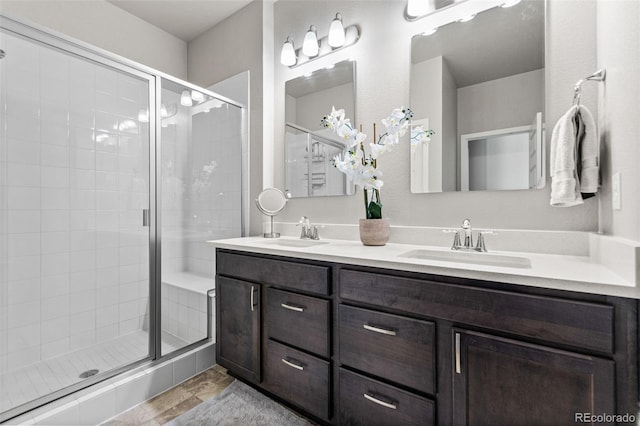 full bathroom featuring a shower stall, double vanity, and a sink