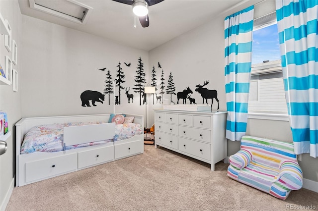 carpeted bedroom with attic access and a ceiling fan