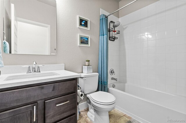 full bath featuring shower / bath combo with shower curtain, toilet, vanity, and a textured wall