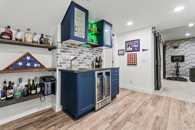 bar featuring wine cooler, wet bar, light wood finished floors, and a sink