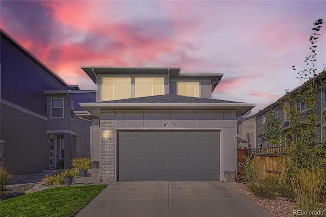 prairie-style house with brick siding, an attached garage, concrete driveway, and fence