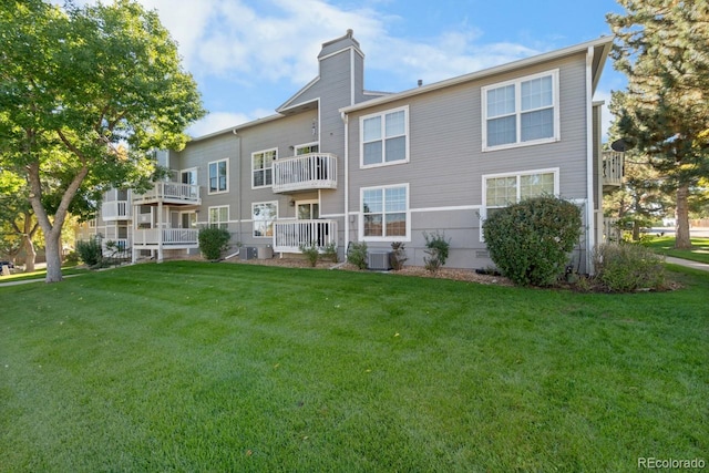 back of house with central AC, a yard, and a balcony