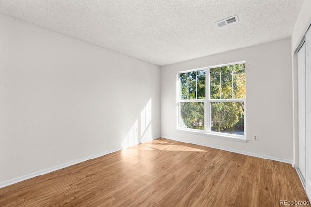 unfurnished room featuring light hardwood / wood-style flooring and a textured ceiling