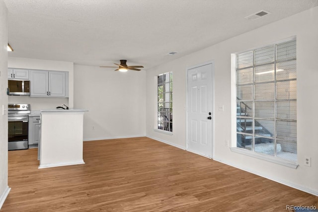 interior space with ceiling fan, light hardwood / wood-style flooring, and a textured ceiling