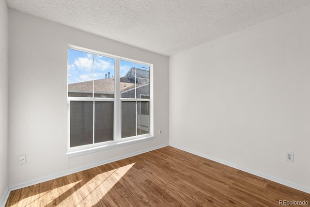 spare room featuring wood-type flooring and a textured ceiling