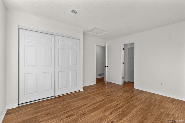 unfurnished bedroom with hardwood / wood-style flooring, a closet, and a textured ceiling