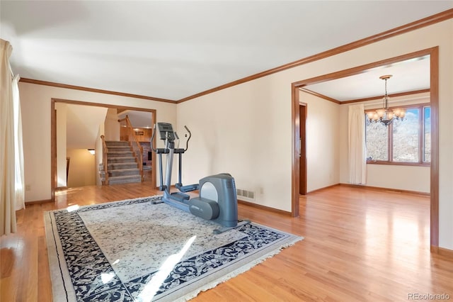 workout area with ornamental molding, light hardwood / wood-style floors, and an inviting chandelier