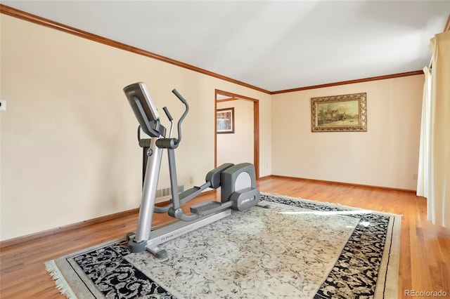 exercise area featuring light wood-type flooring and ornamental molding