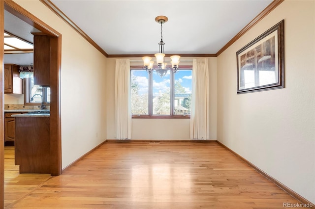 unfurnished dining area featuring sink, ornamental molding, light hardwood / wood-style floors, and an inviting chandelier