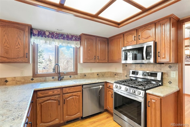 kitchen featuring appliances with stainless steel finishes, light stone counters, and sink