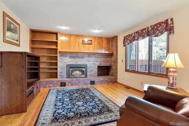 living room with light hardwood / wood-style floors and a brick fireplace