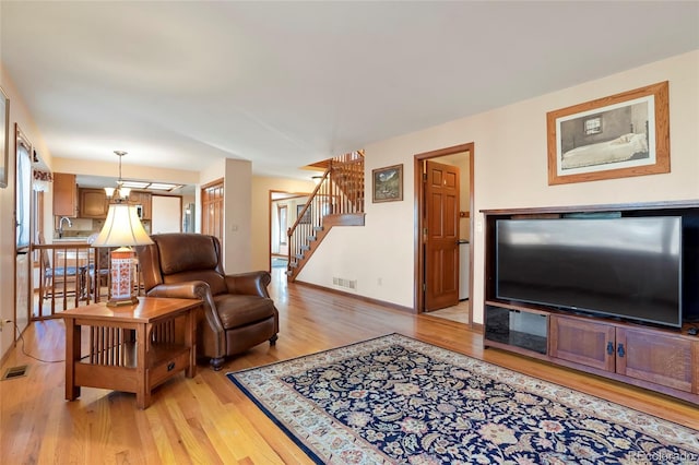 living room featuring light hardwood / wood-style flooring, sink, and an inviting chandelier