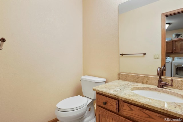 bathroom featuring vanity, separate washer and dryer, and toilet