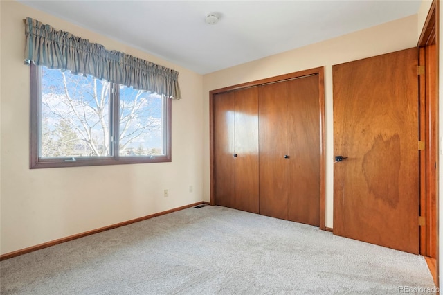 unfurnished bedroom with a closet and light colored carpet