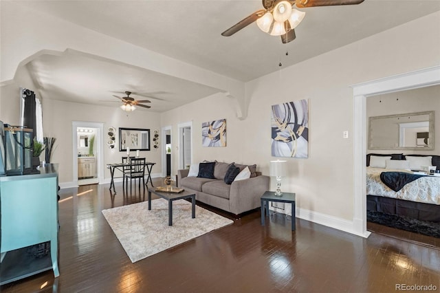 living room featuring ceiling fan and dark wood-type flooring