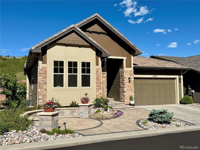 6268 Dakota Ridge Dr, Littleton, CO 80125 - craftsman-style house featuring stone siding, a garage, driveway, board and batten siding, and a tile roof