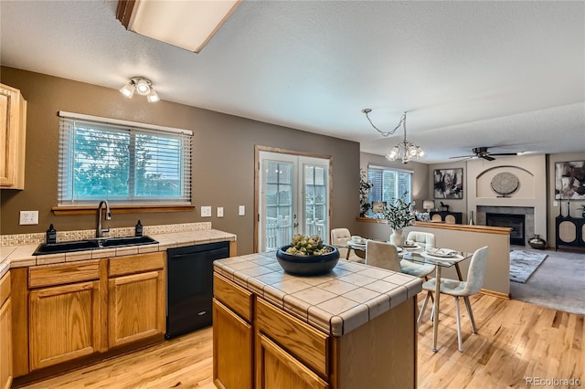 11363 Latigo Ln, Parker, CO 80138 - kitchen featuring black dishwasher, tile counters, open floor plan, a tile fireplace, and healthy amount of natural light