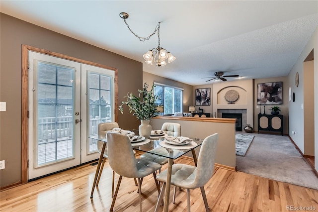 11363 Latigo Ln, Parker, CO 80138 - dining room with a chandelier, light wood-style flooring, french doors, a tiled fireplace, and a ceiling fan