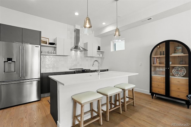 1250 W Osceola St Unit 2, Denver, CO 80204 - kitchen with stainless steel appliances, wall chimney range hood, open shelves, light wood-style flooring, and light countertops