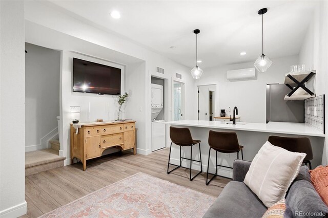 1250 W Osceola St Unit 2, Denver, CO 80204 - kitchen with stacked washer / dryer, fridge, a peninsula, light wood-style flooring, and light countertops