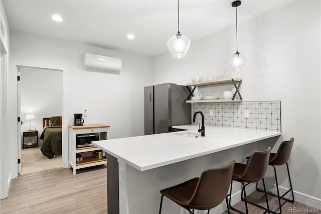 1250 W Osceola St Unit 2, Denver, CO 80204 - kitchen with a wall mounted AC, light wood finished floors, light countertops, a peninsula, and a kitchen breakfast bar