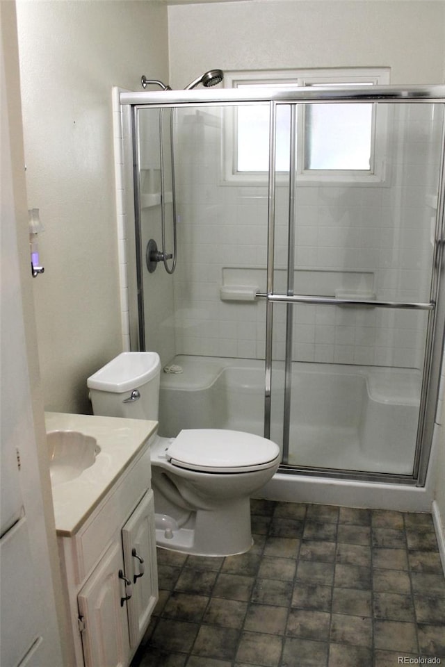 bathroom with a shower with door, vanity, and toilet