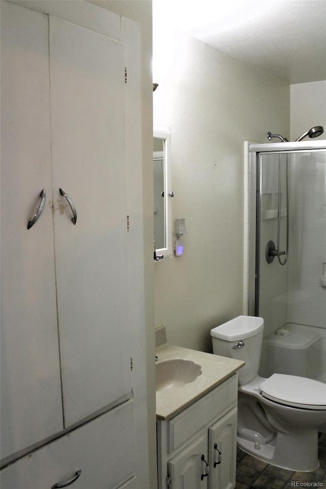 bathroom with a shower with shower door, vanity, and toilet