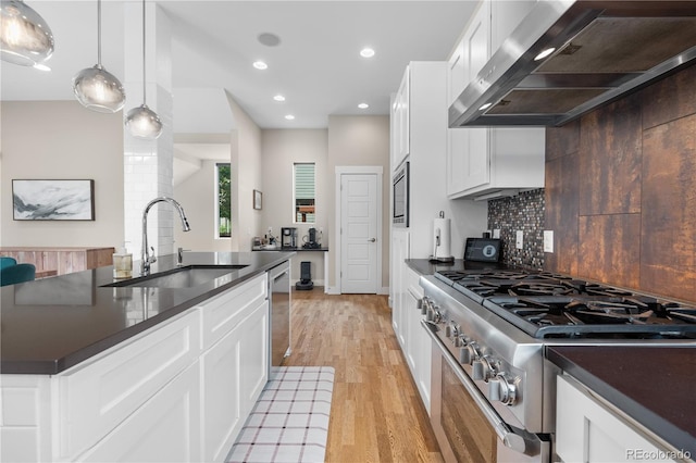 5046 Uinta St, Denver, CO 80238 - kitchen with wall chimney range hood, appliances with stainless steel finishes, dark countertops, light wood-type flooring, and decorative backsplash