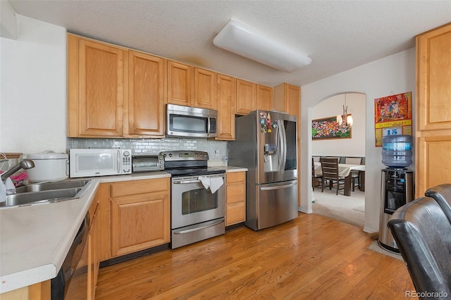 2246 S Ensenada St, Aurora, CO 80013 - kitchen with stainless steel appliances, a sink, light wood-style floors, light countertops, and tasteful backsplash