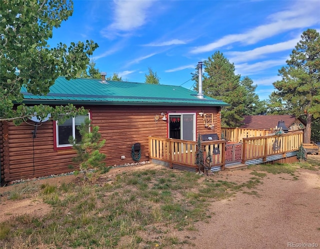 rear view of house featuring a wooden deck, log exterior, and metal roof