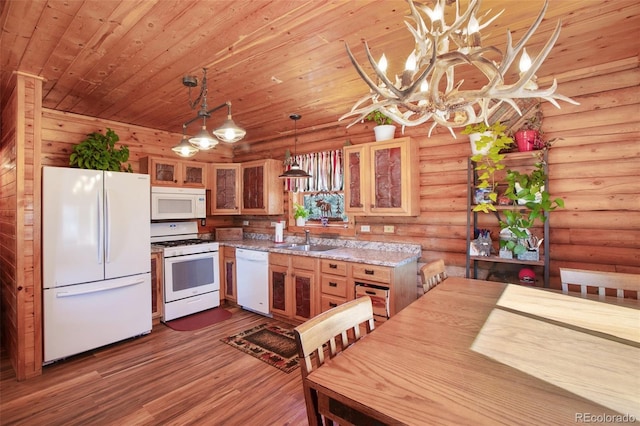 kitchen with a sink, rustic walls, dark wood finished floors, an inviting chandelier, and white appliances