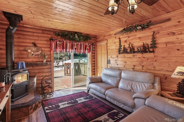living room with hardwood / wood-style floors, a wood stove, log walls, and wooden ceiling