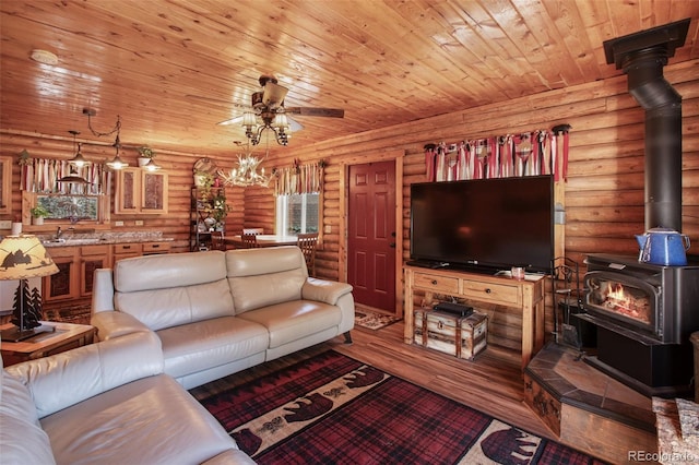 living area with rustic walls, a ceiling fan, wood finished floors, wood ceiling, and a wood stove